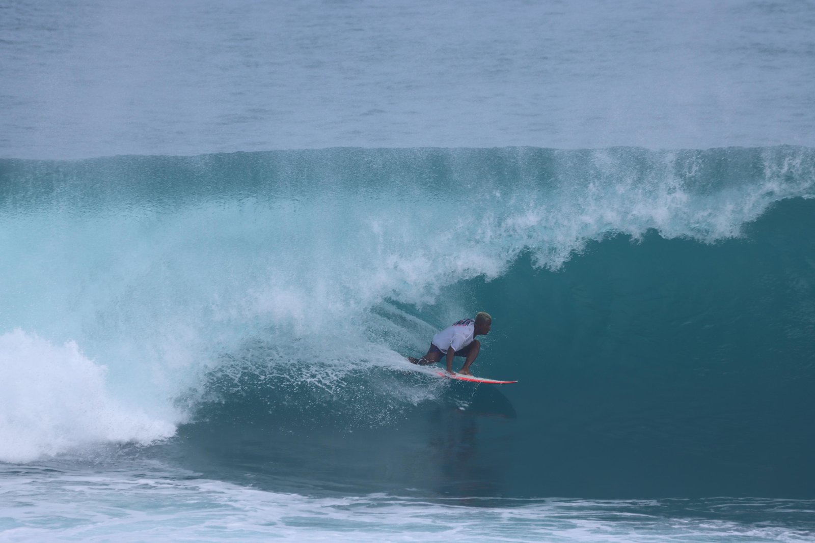 Surfer riding an open face wave with breaking crest at Uluwatu